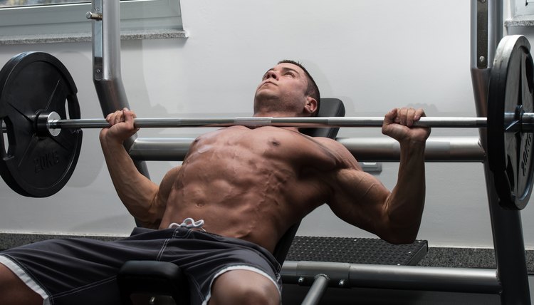 Young Man In Gym Exercising Chest On The Bench Press