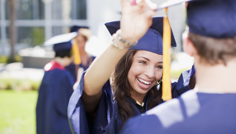 A young woman adjusts her friend's cap at a commencements ceremony.