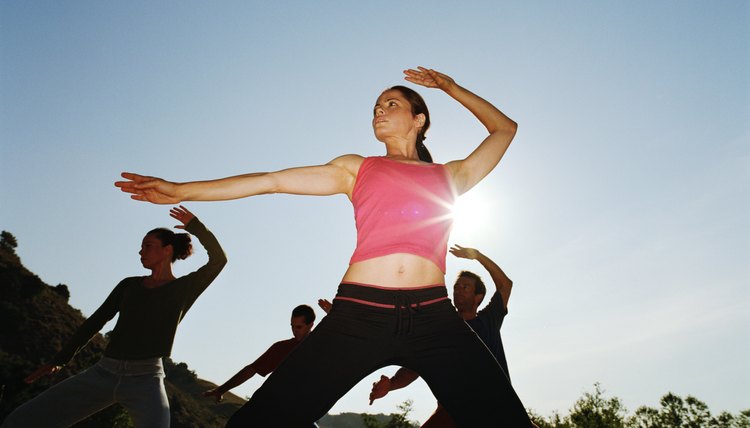 Woman leading group of people in tai-chi position, low angle