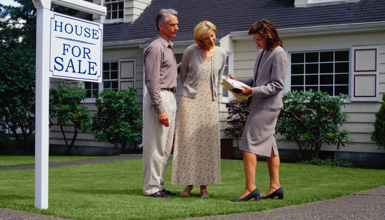 Asesor inmobiliario explica un documento a pareja afuera de una casa en venta.
