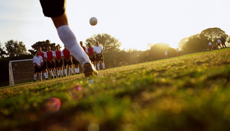 soccer player kicking ball into goal