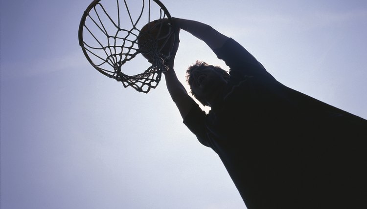Silhouette of man dunking basketball