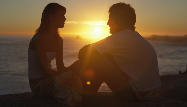 Couple talking near coast at sunset