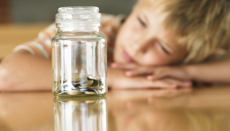 Young boy looking at jar of coins.