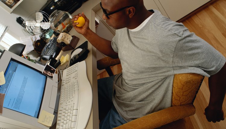 Man Squeezing a Ball While Working on a Computer