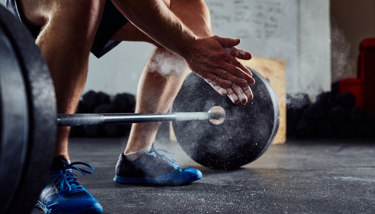 Closeup of weightlifter clapping hands before  barbell workout at the gym