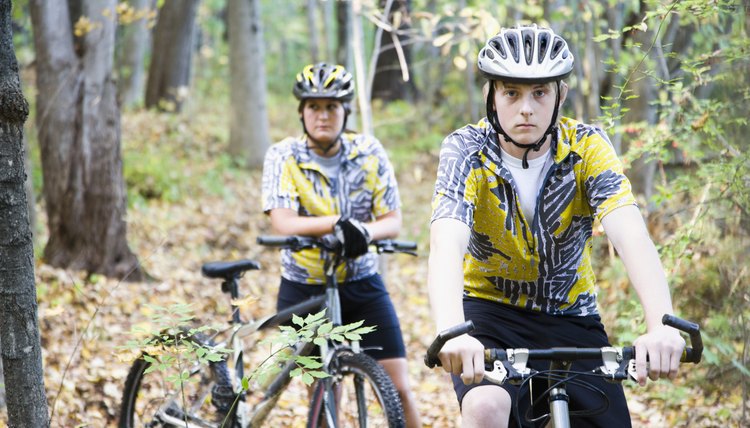Teenage boy and a woman mountain biking through a forest