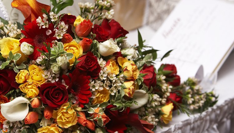 A guestbook on a table next to a large bouquet of flowers.