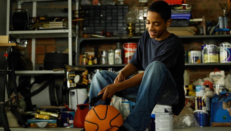 Teenager inflating basketball