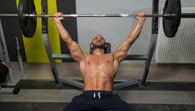 Young Man In Gym Exercising Chest On The Bench Press