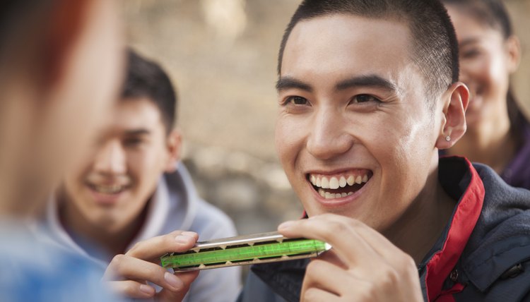 Smiling young man holds a harmonica.