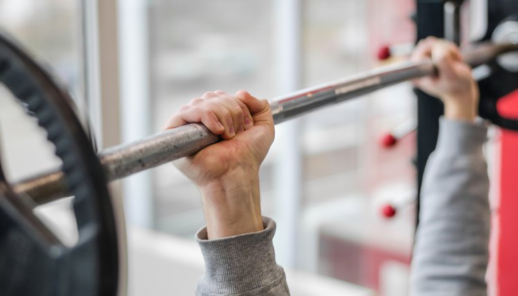 Male arms raising barbell, athlete doing bench press exercise, fitness club