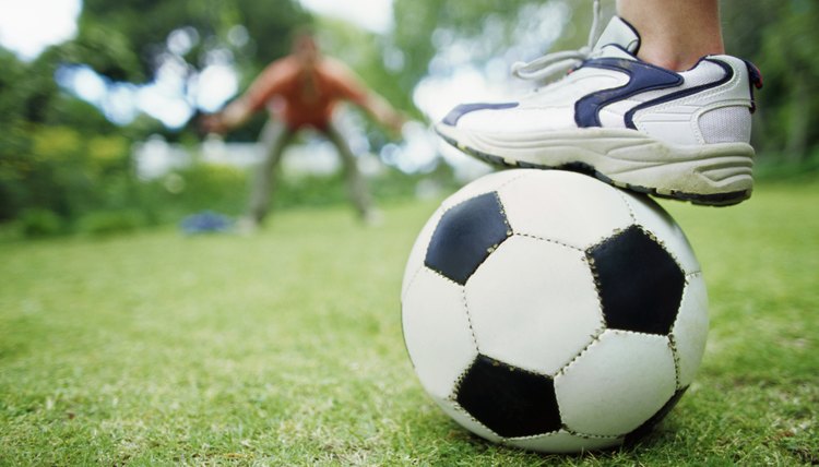 Father and son playing soccer in garden (10-11)