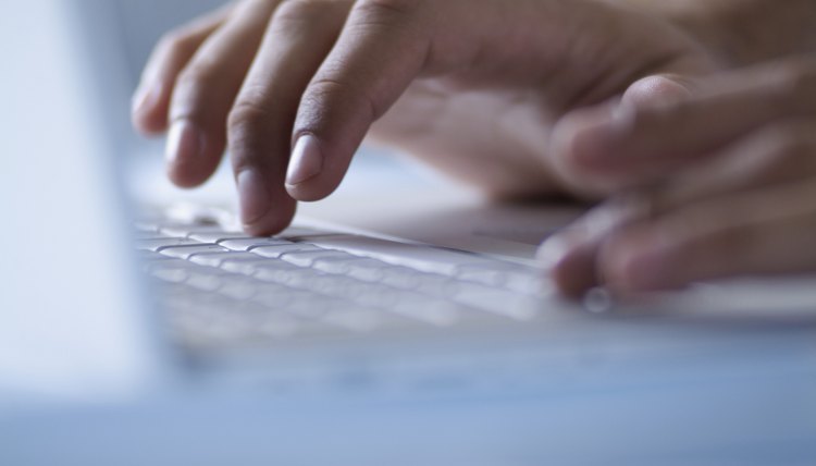 Hands typing on laptop computer, close-up