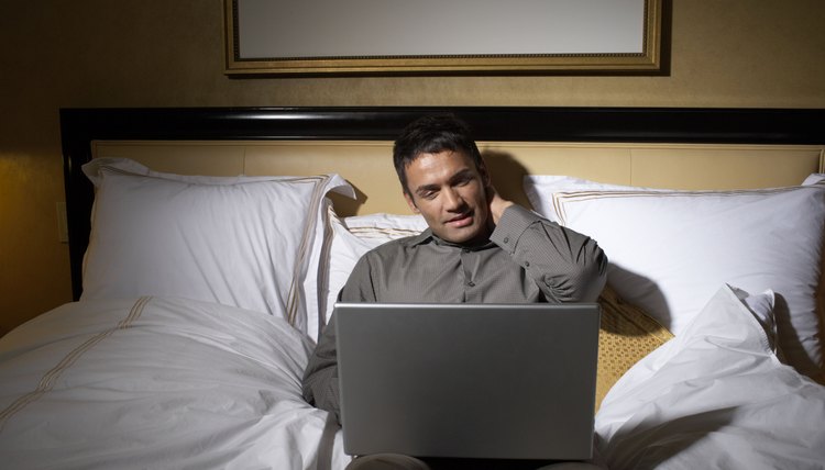 Man lying on bed, using laptop