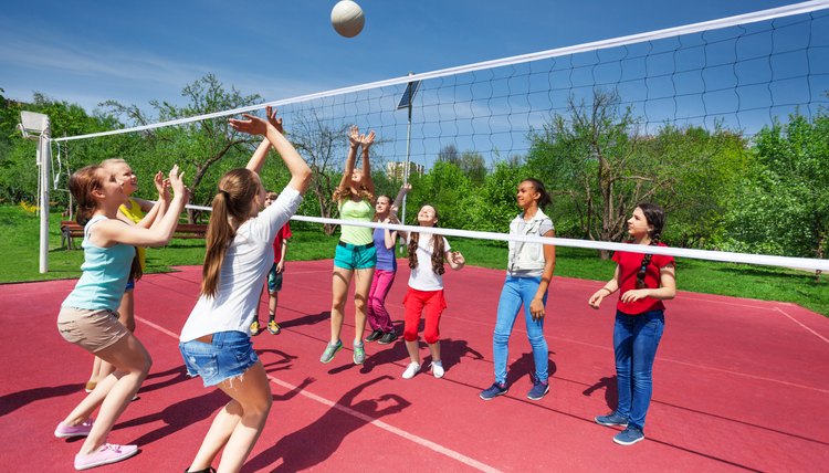 Teenage girls and boy play together volleyball