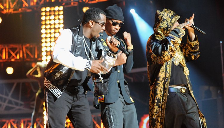 Three hip hop artists perform on stage.