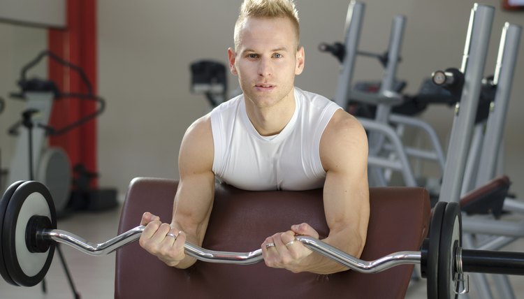 Handsome young man training biceps in gym