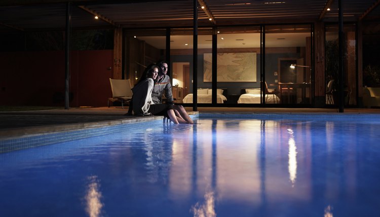 Young couple sitting at edge of pool at night