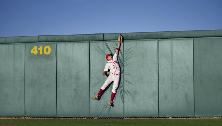 USA, California, San Bernardino, baseball player making leaping catch at wall