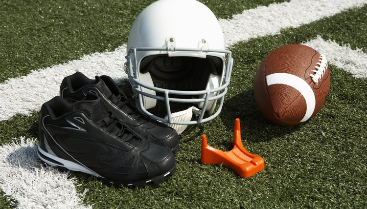 Football, football helmet, tee and shoes on football field