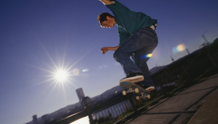 Teenage boy (16-17) performing tricks with skateboard on sidewalk, low angle view