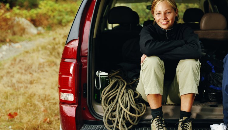 Femal rock climer sitting with gear in back of SUV, portrait