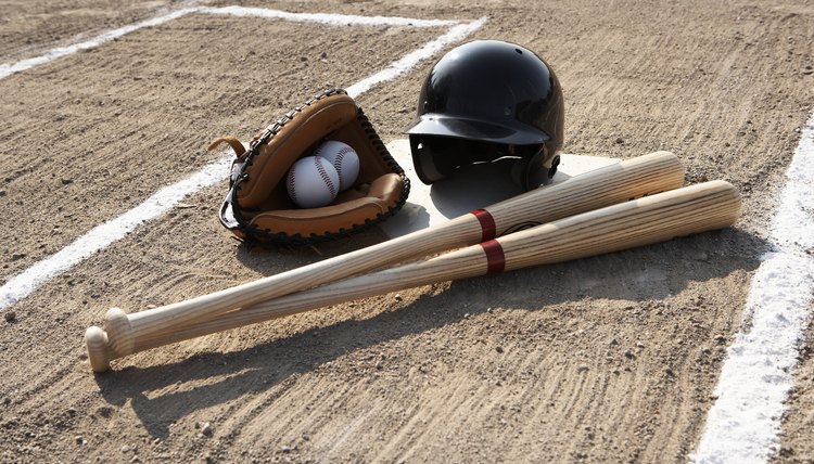 Baseball glove, balls, bats and baseball helmet at home plate