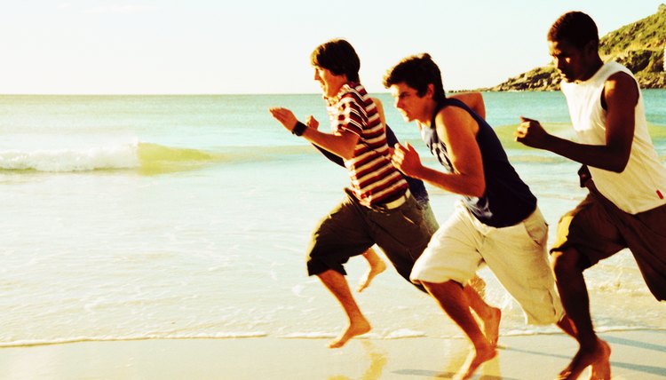 three teenage boys racing each other on the beach