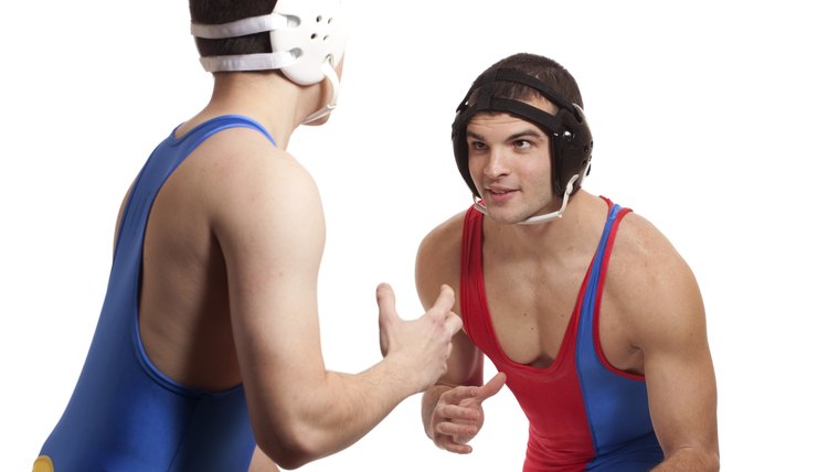 Men in wrestling tights holds the boy with one hand and they both