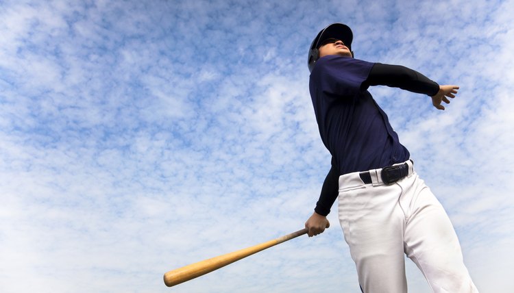 baseball player taking a swing with cloud background