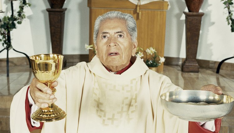 An Elderly Priest Blesses Communion Wine in a Golden Cup and Bread in a Silver Bowl