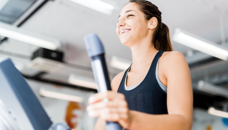 Beautiful young lady using the elliptical trainer