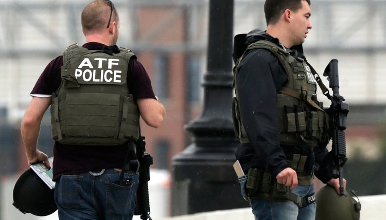 ATF agents carrying guns and wearing bulletproof vests.