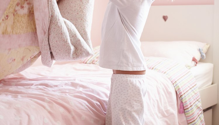 A girl makes her bed in the morning.