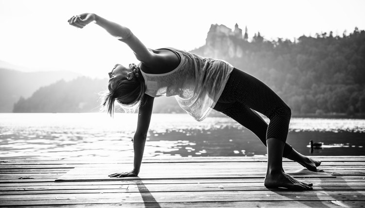 Young woman doing yoga by the lake. Black and white image