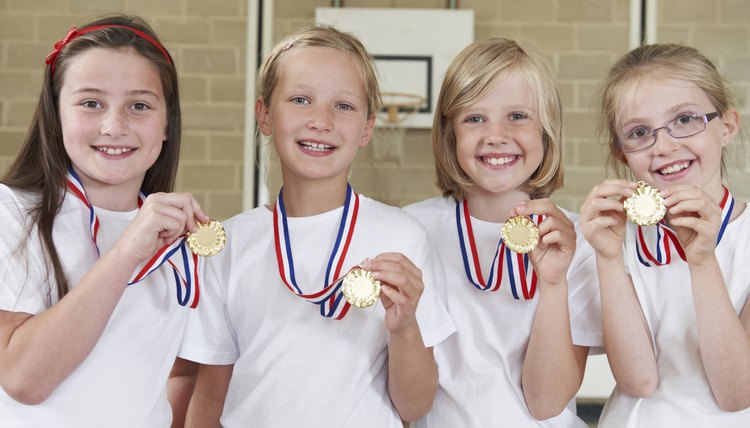Female School Sports Team In Gym With Medals