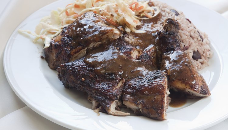 A plate of jerk chicken with rice, beans and coleslaw.