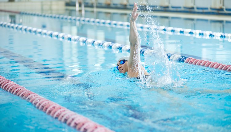 Young girl in goggles swimming front crawl stroke style