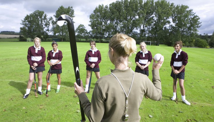 Coach holding field hockey stick and ball team