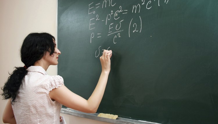 A teacher writes equations on a chalkboard.