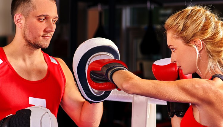 Female boxer  throwing  right cross at mitts