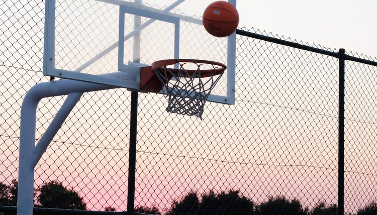 Basketball hoop with a ball at sunset.