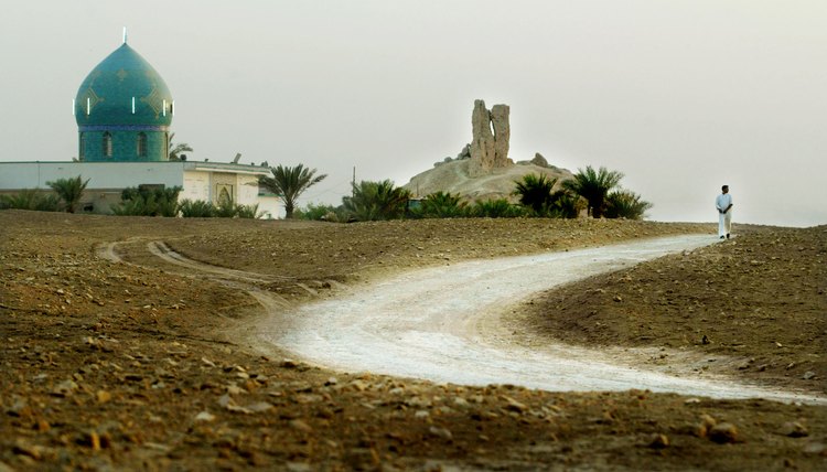 A road winds through a Mesopotamian landscape by an ancient shrine.