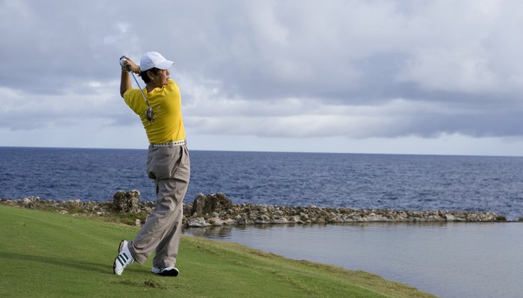 Mature man playing golf on golf course, looking away