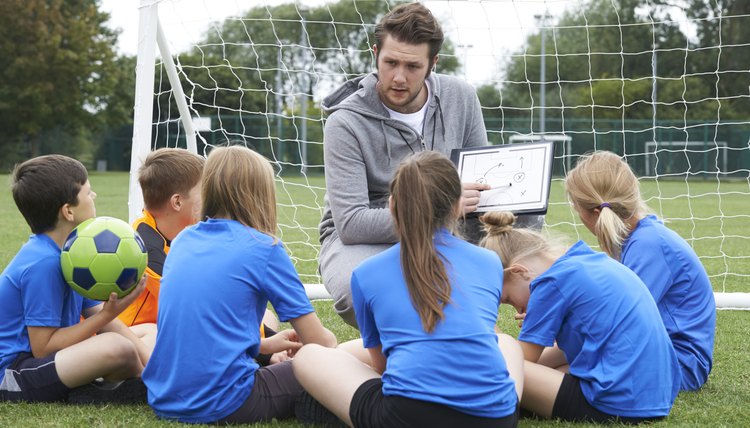 Coach Giving Team Talk To Elementary School Soccer Team