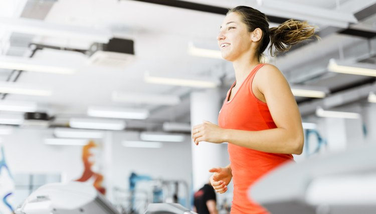Beautiful young woman running on a treadmill in gym