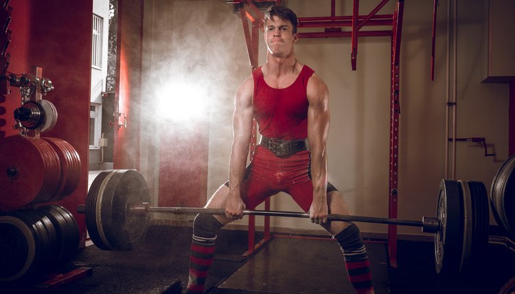 Young adult man doing heavy sumo deadlift exercise in gym club.