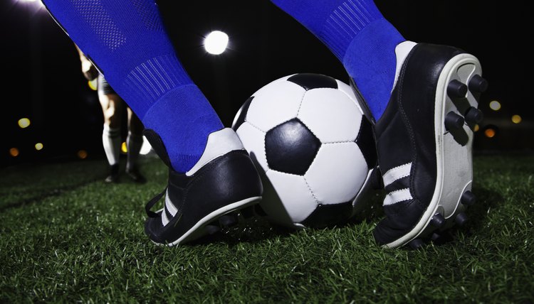 Close up of feet kicking the soccer ball, night time in the stadium