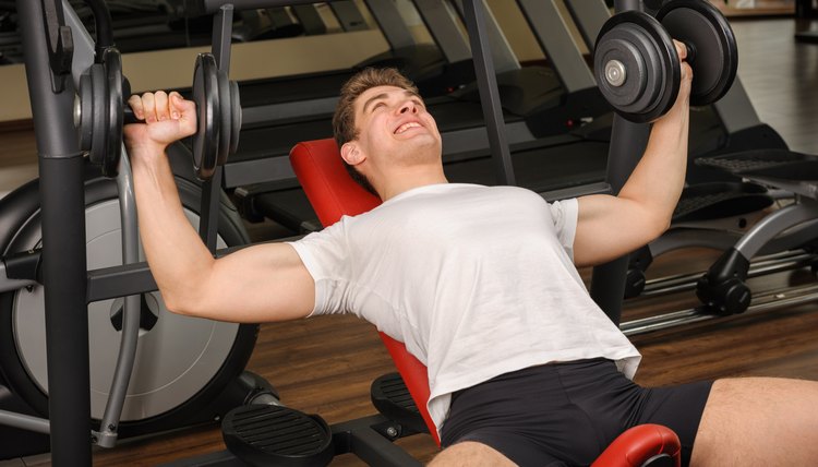 Handsome young man doing Dumbbell Incline Bench Press workout in gym